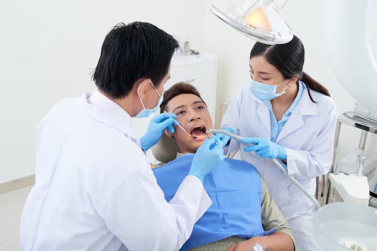 ทันตแพทย์และผู้ช่วยกำลังตรวจฟันให้คนไข้